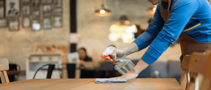 waiter sprays disinfectant to clean table