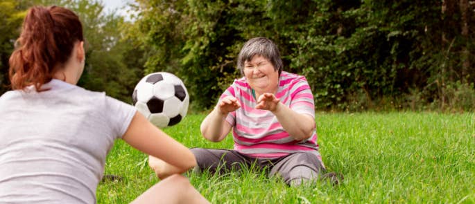 Woman and her carer playing football in the park