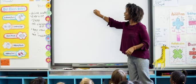Teacher writing on the interactive whiteboard in classroom