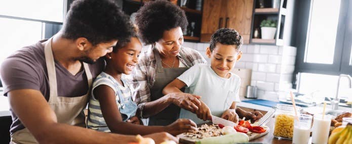 A family with two young children cooking together in a kitchen