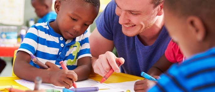 Male nursery teacher drawing with two children.