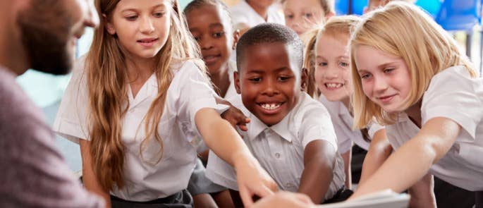 Group of children reading a book together in class