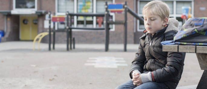 Young child sitting sadly on bench