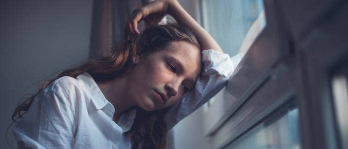 Sad child leaning on window