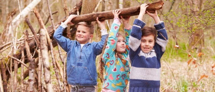 Children working together to make a shelter with big log