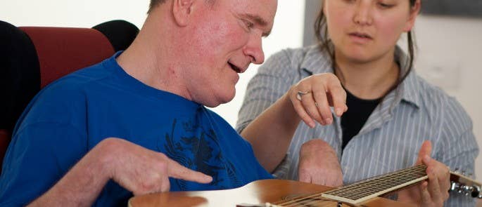 Gentleman with disability playing guitar in music therapy session