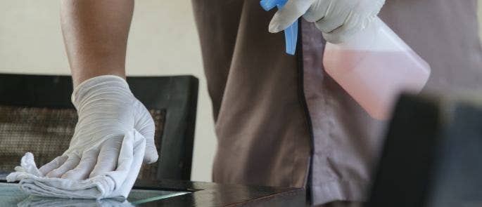 Worker cleaning surface with spray and cloth