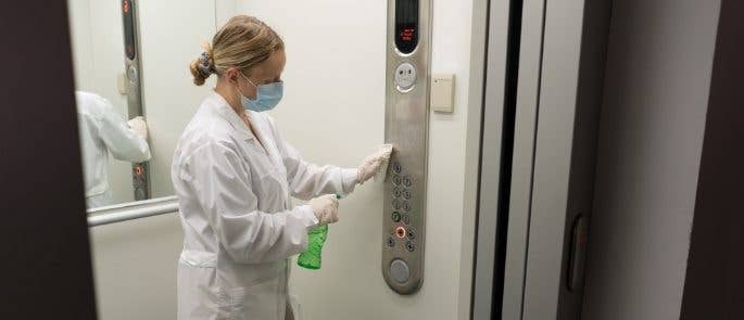 Worker cleaning lift buttons