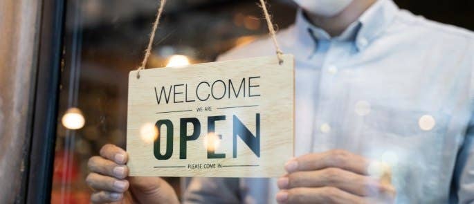Worker displaying open sign in shop window