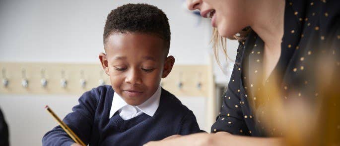 Teacher supporting a child with learning in the classroom