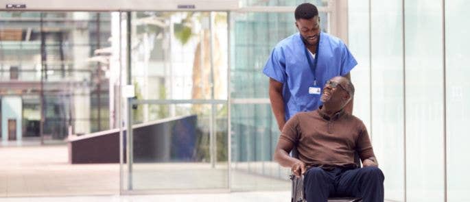 Nurse pushing patient in a wheelchair through hospital lobby