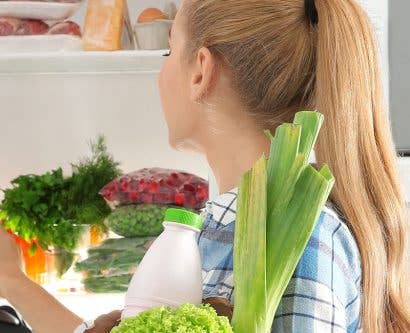 a woman storing food away in the fridge