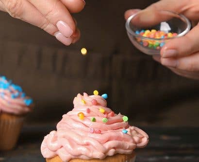 food additives being sprinkled on a cupcake