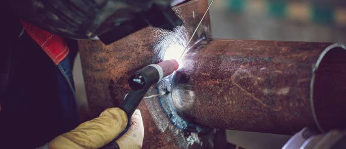 Worker carrying out hot work while welding metal pipe