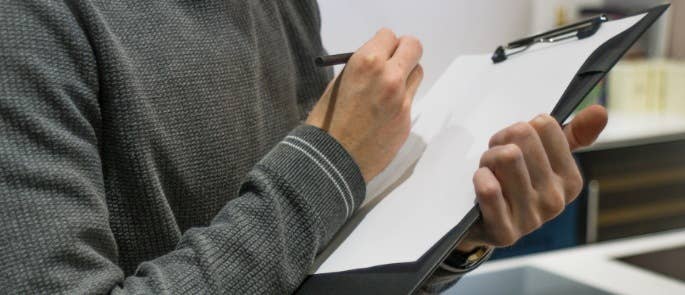 Person standing with clipboard and pen