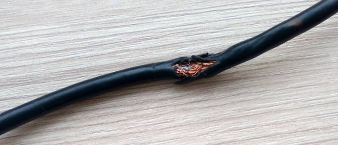 Damaged black cord with wires exposed