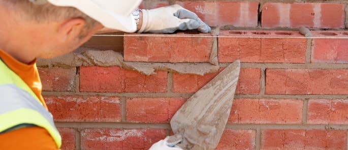 Bricklayer laying bricks and mortar