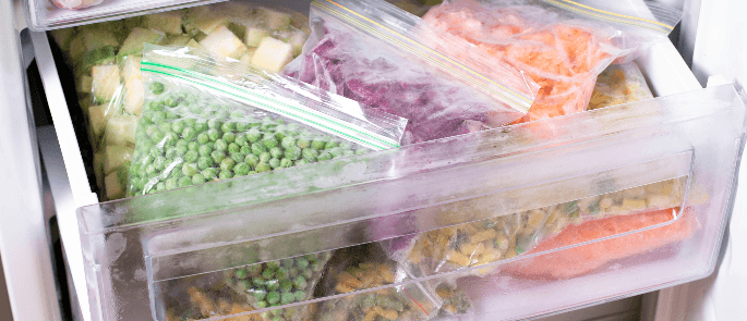 a freezer drawer with sealed bags of vegetables