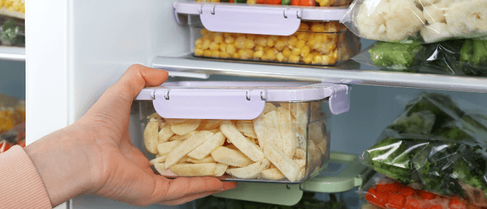 storage containers full of food being placed in a freezer