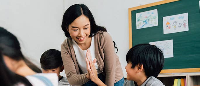 A teacher and a child high fiving 