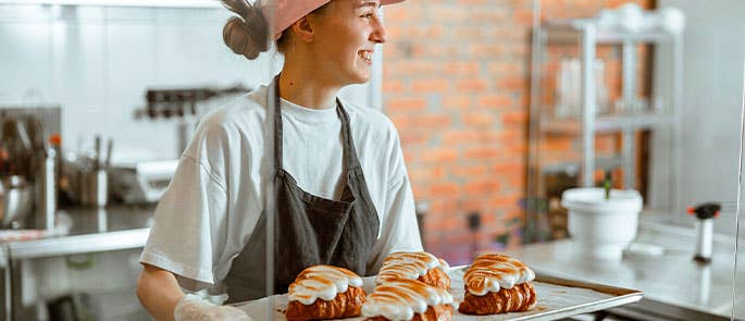 Baker smiling holding a tray of fresh pastries