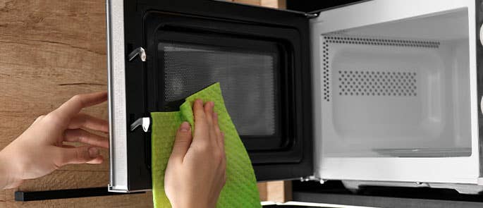 Microwave being dried after cleaning with a dry cloth