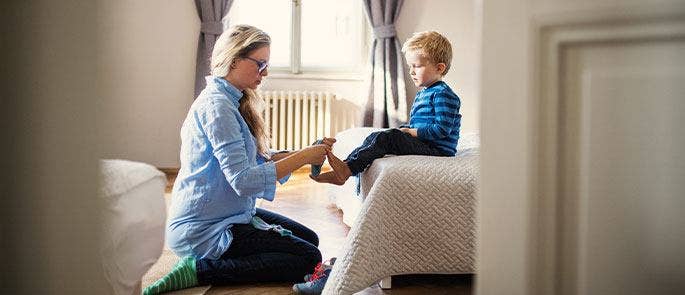 A mother helping her young son with putting on his shoes and socks