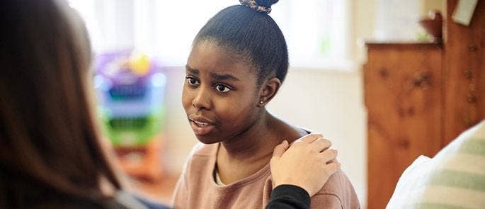 Teenage girl speaking to a member of staff at school for support