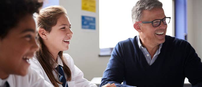 two children and their teacher in a classroom laughing
