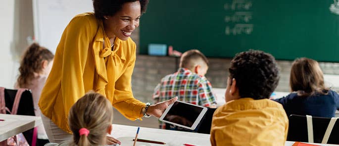 primary school teacher teaching pupils with an ipad