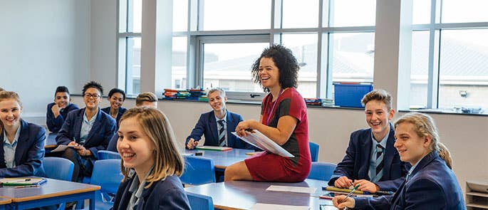 Secondary school teacher in happy classroom with students