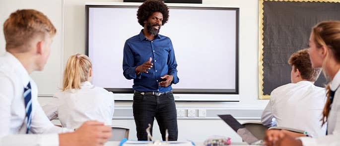 Teacher at head of classroom teaching to students