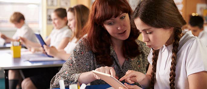 teacher helping student in classroom