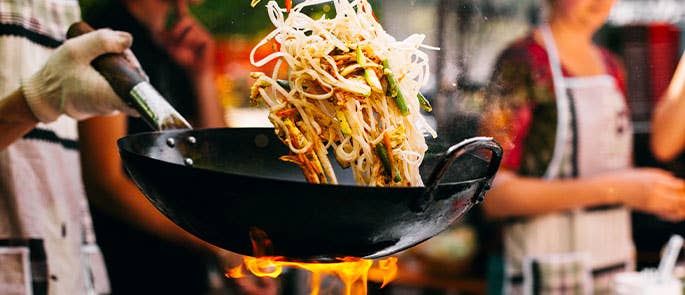 chef stir frying noodles and vegetables in a restaurant