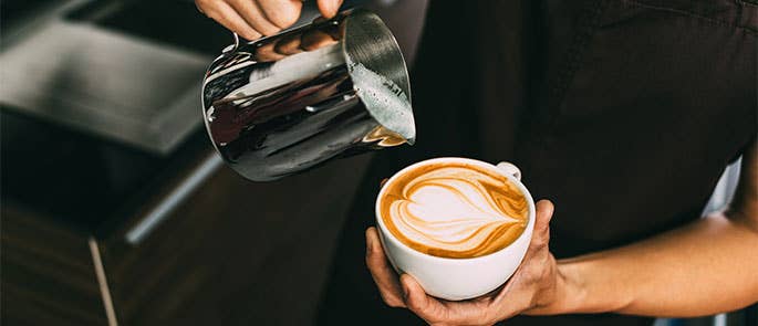 barista working in cafe doing latte art