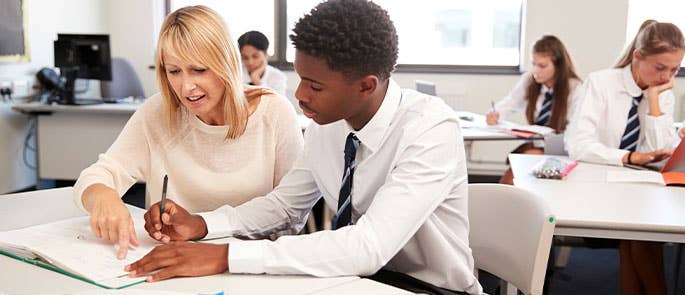 Teacher sat with student instructing on some work