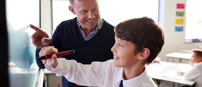 Teacher stood at white board with pupil