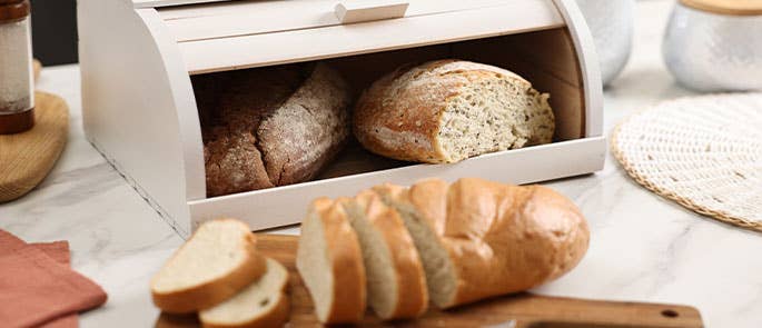 Bread being sliced and stored in a bread bin