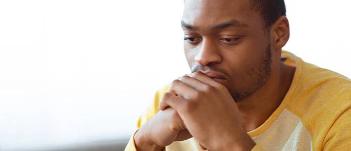 Man who is experiencing negative thoughts and looks down or upset