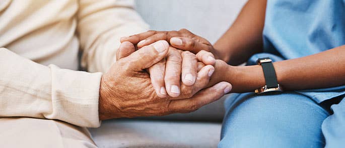 Healthcare worker holding elderly persons hands