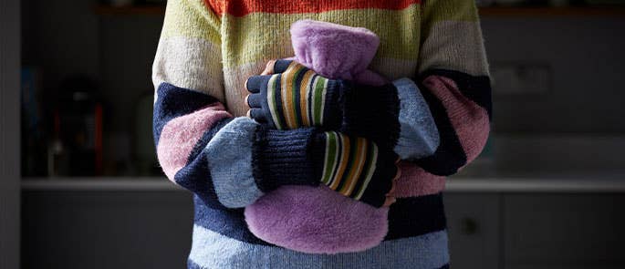 Someone holding a covered hot water bottle to keep warm