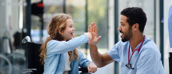 nursery nurse high fiving with child in wheelchair