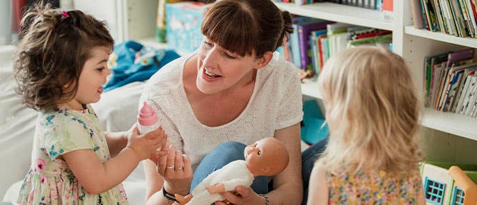 childminder playing with dolls with children