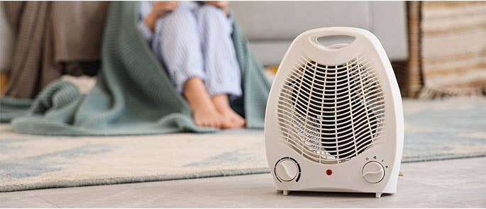 person getting warm near portable heater