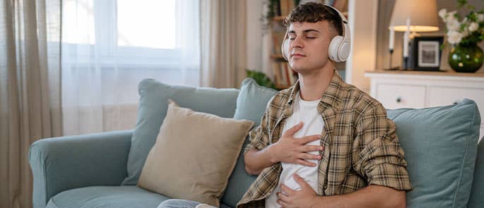 Man practicing self care by meditating listening to music