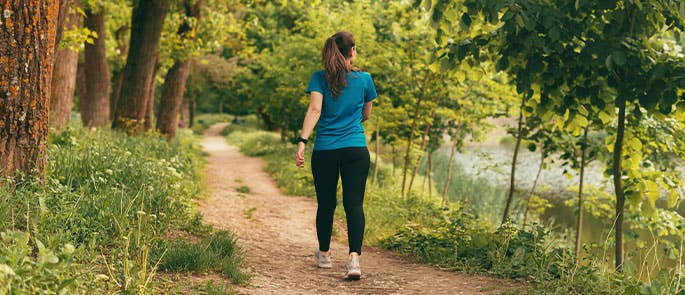 woman practicing self care by walking in nature