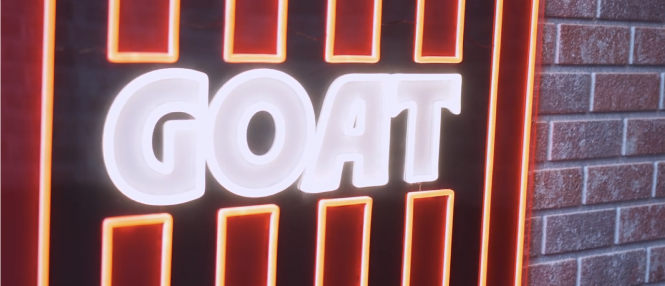 brick wall with neon GOAT sign