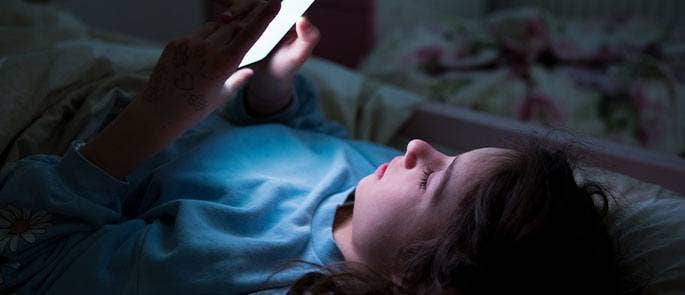 Young girl using her phone in bed