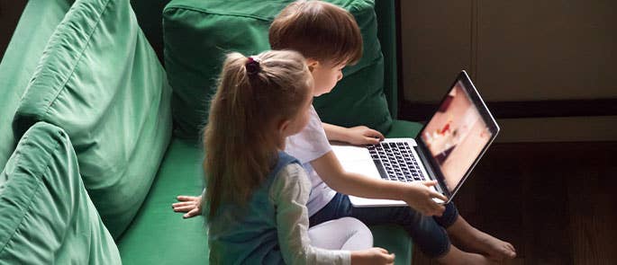two young children watching YouTube on laptop in living room