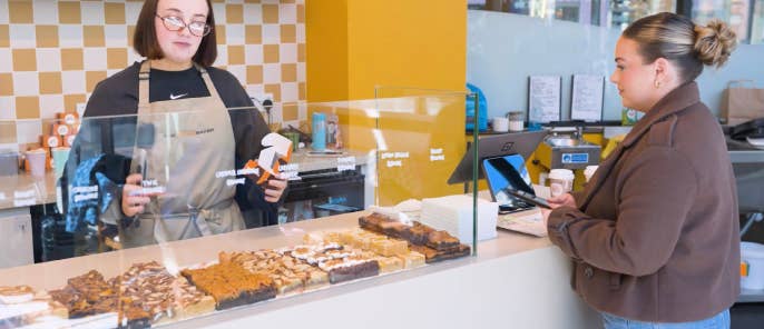 Customer buying a brownie from employee at The Savvy Baker